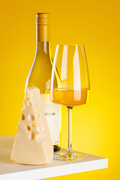 White wine with cheese pieces on yellow background gourmet composition