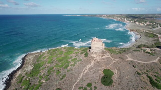 Drone orbiting the ancient Spanish watchtower of Torre di San Giovanni di Sinis, overlooking the beautiful Mediterranean sea in Sardinia, Italy