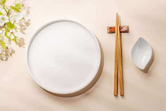 Empty white plate with chopsticks and blue bowl