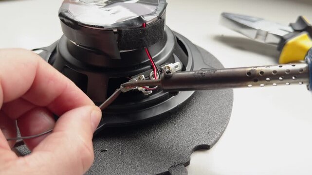Technician soldering audio speaker wire with iron