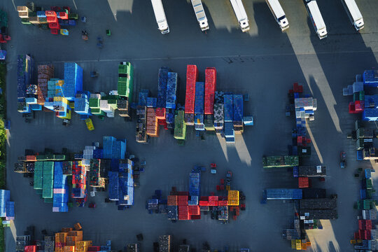 Panoramic view of a large modern distribution center. Many trucks park at loading docks. Forklifts actively manage cargo, showcasing logistics and freight operations.