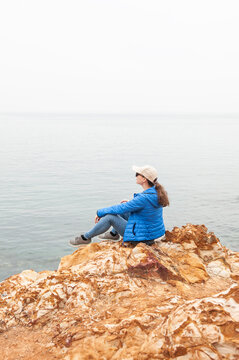 Adventure woman sitting on rocky coastline
