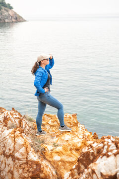 Adventure woman standing on rocky coastline