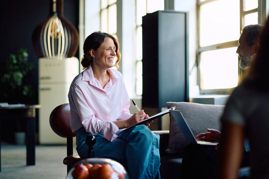 Happy businesswoman and her colleague talking while working in office.