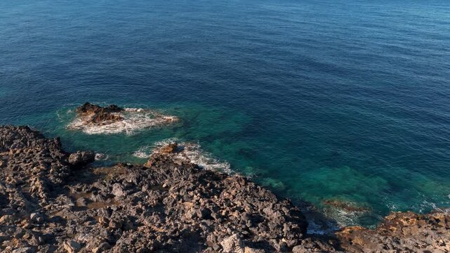 Crete Island coastline aerial video, with waves splashing on rocks, above view
