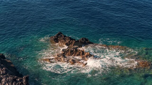 Drone aerial video on Crete island coastline, with waves splashing on rocks, above view
