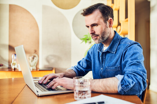 Man working on laptop at dining table at home