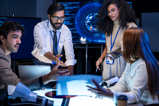 A multiethnic technology developer team holding and inspecting a raw silicon wafer disk to check semiconductor circuit microchip fabrication logic parameters in a workspace.