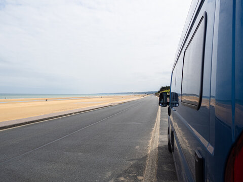 Vista de la playa Omaha Beach, protagonista del desembarco de Normand&iacute;a en la segunda guerra mundial, furgoneta azul en la carretera oscura y playa dorada, viajando en verano 2022