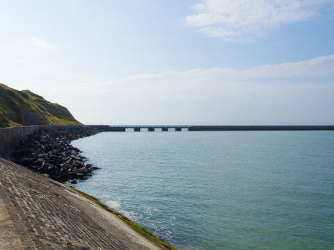 Paisaje de la costa normanda en Francia, con un puente en el horizonte sobre el mar azul y el cielo con nubes, viajando en verano de 2022