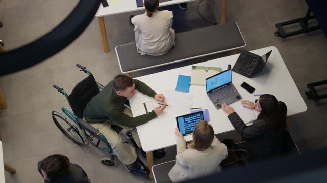 Business people are working collaboratively around a modern office table. A diverse team is engaged in a productive meeting using technology.