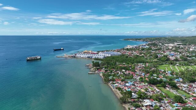 Land grabbing drone Danao Cebu Philippines over populated population cluster of building and houses poor people squatter coastal port boat ships cargo passengers sailing blue sky and sea residential