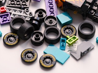Obraz premium Tambov, Russian Federation - January 01, 2026 A pile of Lego black plastic toy Chevrolet Camaro car wheels, tires, and colorful bricks scattered on a white surface.