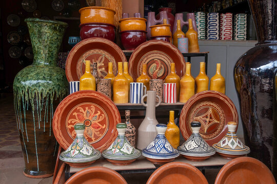 Vibrant display of traditional Moroccan pottery, including hand-painted tagines, colorful vases, and ornate ceramic jugs at a local market stall.
