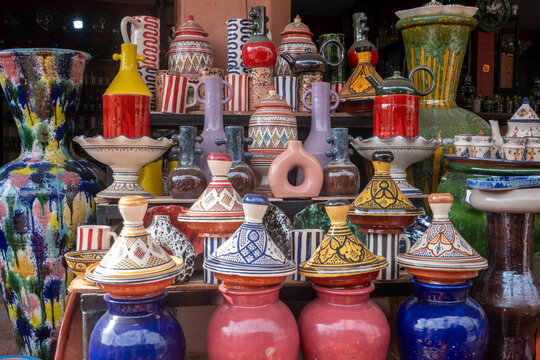 Vibrant display of traditional Moroccan pottery, including hand-painted tagines, colorful vases, and ornate ceramic jugs at a local market stall.
