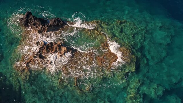 Mediterranean sea drone aerial video on Crete island, with waves splashing on rocks, above view

