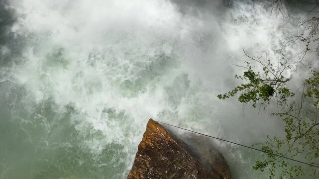 A bird's-eye view of the water cascading down from the top of the waterfall, foaming with vigor.