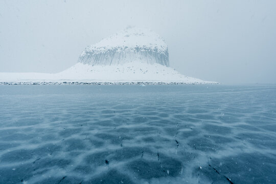 Edinburgh Hill basalt columns in Antarctica in snowy conditions with sea ice forming in the foreground