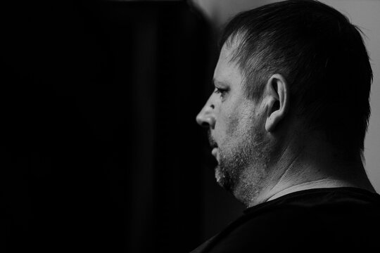 Birini, Latvia - May 24, 2026: Profile view of a middle-aged man with short hair and beard, captured in black and white against a dark background