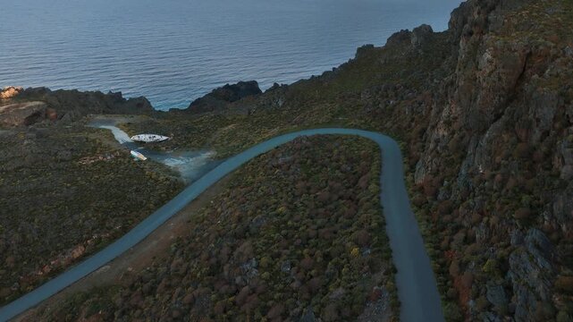 Sunrise scenery on the coastline of Island Crete with winding road through the high mountains, drone aerial view
