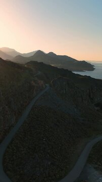 Vertical aerial video with scenic winding road in Cretan mountains on the coastline
