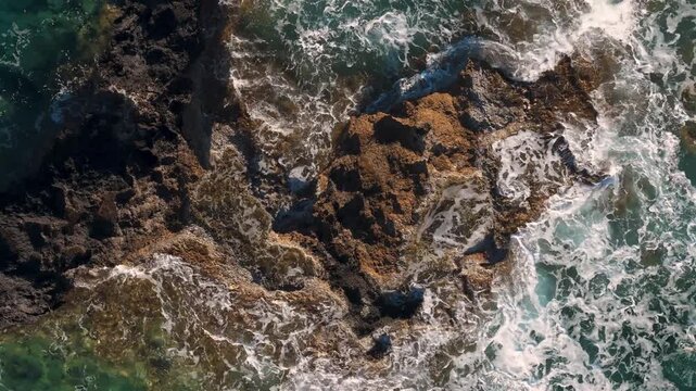 Waves splashing on rocks in the Mediterranean sea, close-up aerial video on Crete Island coast

