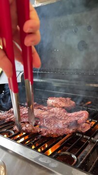 Hand grilling juicy skirt steak on fiery barbecue