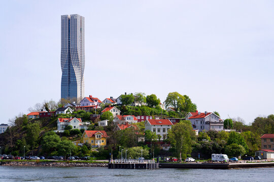 Colony of small wooden historic houses on the Slottsberget mountain with the tallest Scandinavian building Karlatornet skycraper in Lindholmen in background, Gothenburg, Sweden