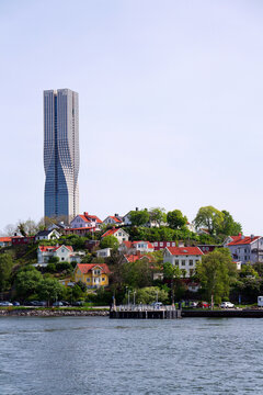 Colony of small wooden historic houses on the Slottsberget mountain with the tallest Scandinavian building Karlatornet skycraper in Lindholmen in background, Gothenburg, Sweden