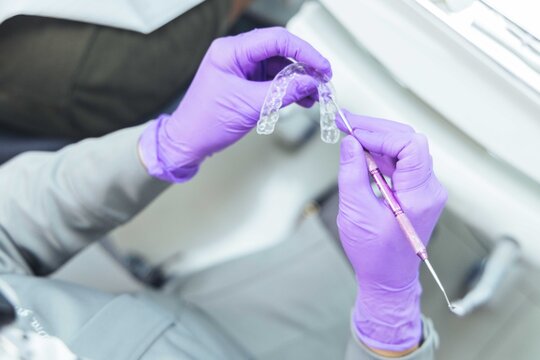 Las manos de una dentista con alineadores invisibles 