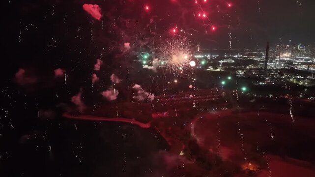 Aerial flies forward into a spectacular, close-up barrage of exploding golden fireworks and smoke over Ashbridges Bay Park, framing the illuminated Toronto cityscape at night