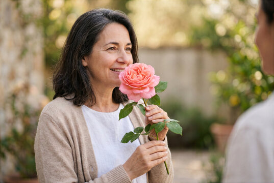 Konzeptbild zur Redewendung &bdquo;etwas durch die Blume sagen&ldquo;, bei dem eine Person wortw&ouml;rtlich durch eine Blume spricht.
