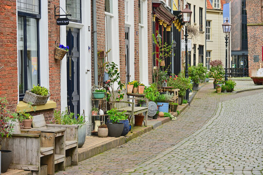 Charming historic cobblestone street with traditional brick houses and colorful potted plants in the IJssel river valley area between Kampen and Doesburg, Netherlands scenery