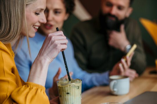 Young friends connecting and having drinks in a coffee shop