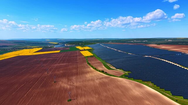 Brown, yellow, blue and green patches in the landscape. Huge nature territory is covered with solar panels. Aerial view.