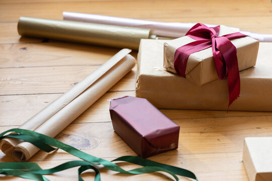 Close-up scene showing stacked kraft-paper wrapped gift boxes with deep-red satin bow on tabletop
