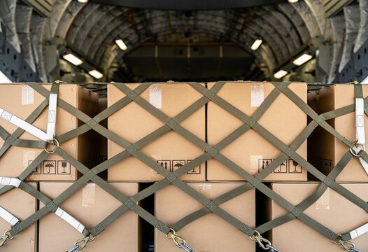 Cardboard boxes securely fastened with cargo straps inside the large hold of an aircraft transport.