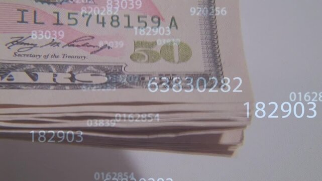 Camera shifting and tilting, revealing stack of US 50 bills while numbers drifting to show serials