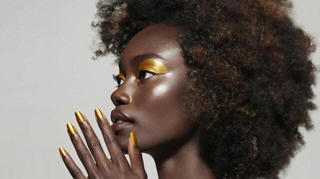Beautiful african woman with golden makeup and closed eyes posing in dramatic studio lighting against dark background Concept of luxury beauty