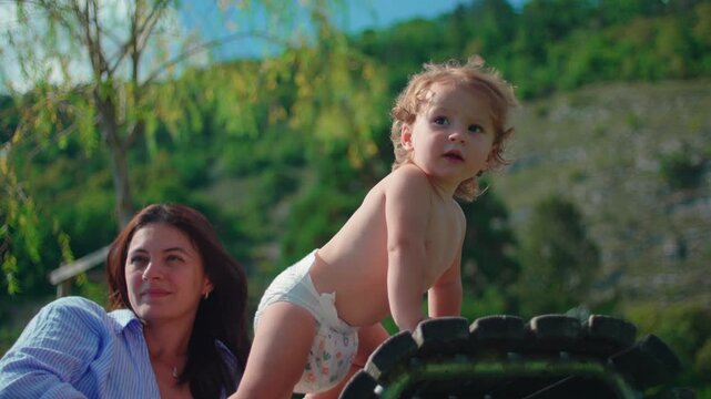 Toddler standing confidently on curved outdoor lounge chair during sunny lakeside afternoon capturing balance development, curiosity and carefree summer childhood freedom