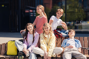 Diverse group of smiling happy teenagers sitting on the street posing looking at camera © Maria Vitkovska