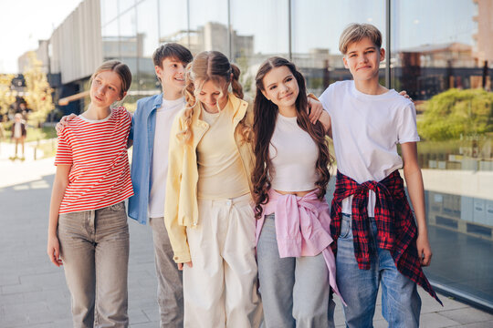 Diverse group of smiling happy teen boys and girls walking together on the street in urban city