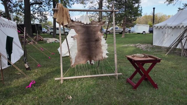 Metropolis, United States - 14 January 2026: View of an animal hide stretched on a wooden frame for tanning with canvas tents in the background at Fort Massac State Park.