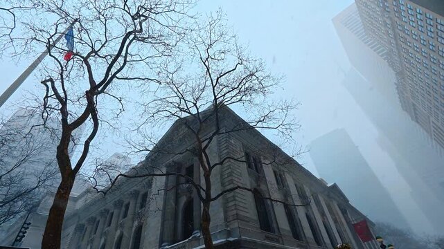 Watching grey sky with snow falling. Low angle view on the skyscrapers disappearing into the fog. New York City, USA.