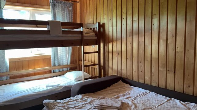 Warm forest cabin with wooden walls, white bedding, double bed and bunk bed designed for comfortable outdoor travel and cozy family accommodation.