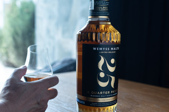 Wemyss Malts 25 years old Scotch whisky bottle with a hand holding a tasting glass on a wooden table. Premium luxury alcohol photography. Ukraine, Zhytomyr, May 21, 2026