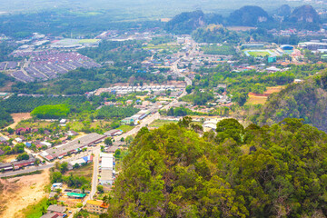 Fototapeta premium High angle view of a town nestled among green limestone mountains in Krabi Thailand. aerial townscape, tropical tourism, scenic viewpoint.