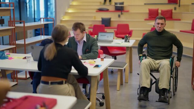 A diverse group of professionals are actively engaged in collaborative work within a modern office setting. This scene highlights teamwork and inclusivity among colleagues in a dynamic workplace.
