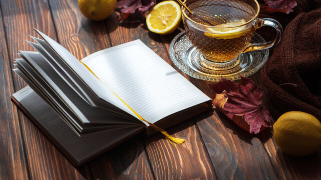 Cozy autumn morning with notebook, tea, and falling leaves