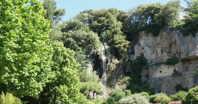 Cascade de Villecroze dans le Haut Var le long de la paroi d'une haute falaise avec grottes troglodytiques et terrasses dominant un parc arbor&eacute; et verdoyant
